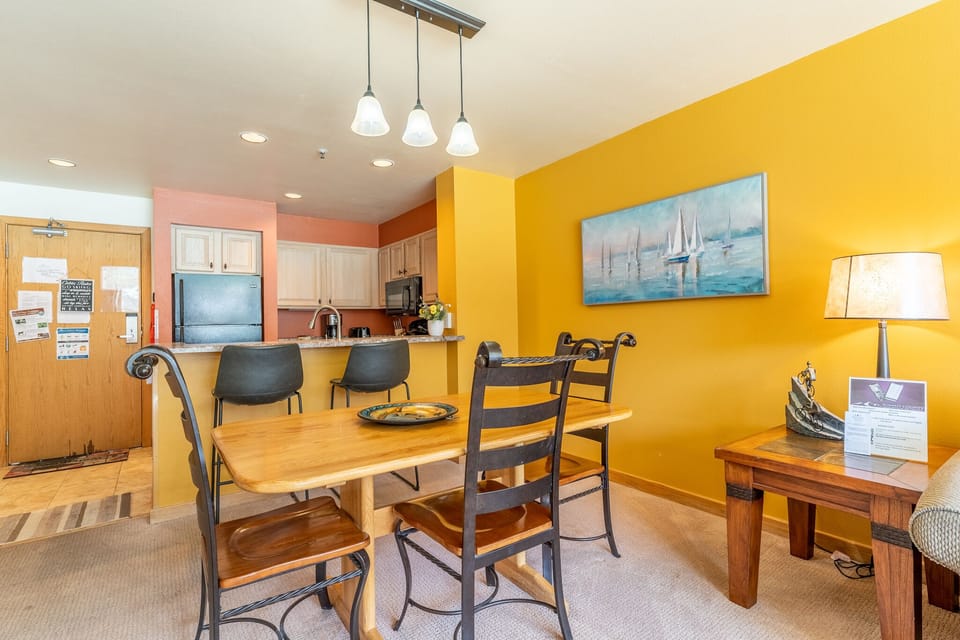Gather around your sunny dining space with vibrant yellow walls and warm wood furnishings, perfect for morning coffee or evening meals.