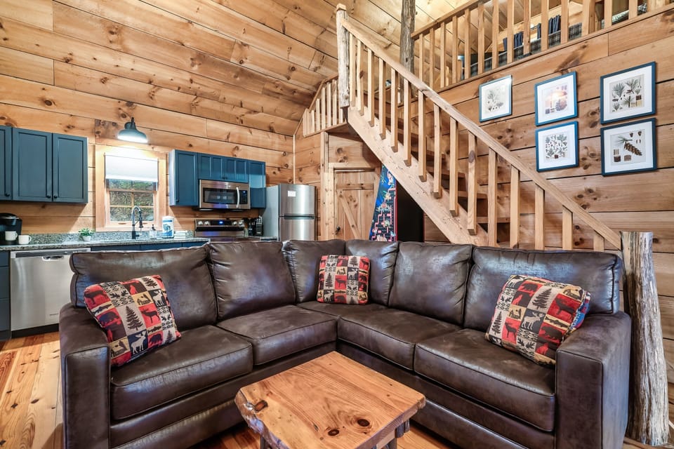 Spacious living area with leather sectional and loft above