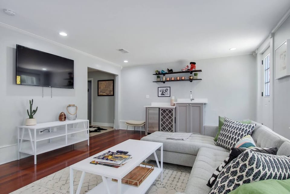 Living room with sectional sofa, wet bar, big screen smart tv, and rear courtyard access.