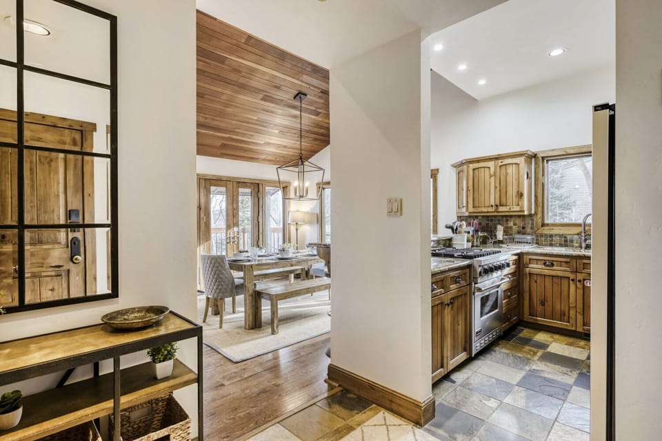 Step into this warm, rustic kitchen where wood cabinets and stone floors create a cozy mountain retreat atmosphere for your culinary adventures.
