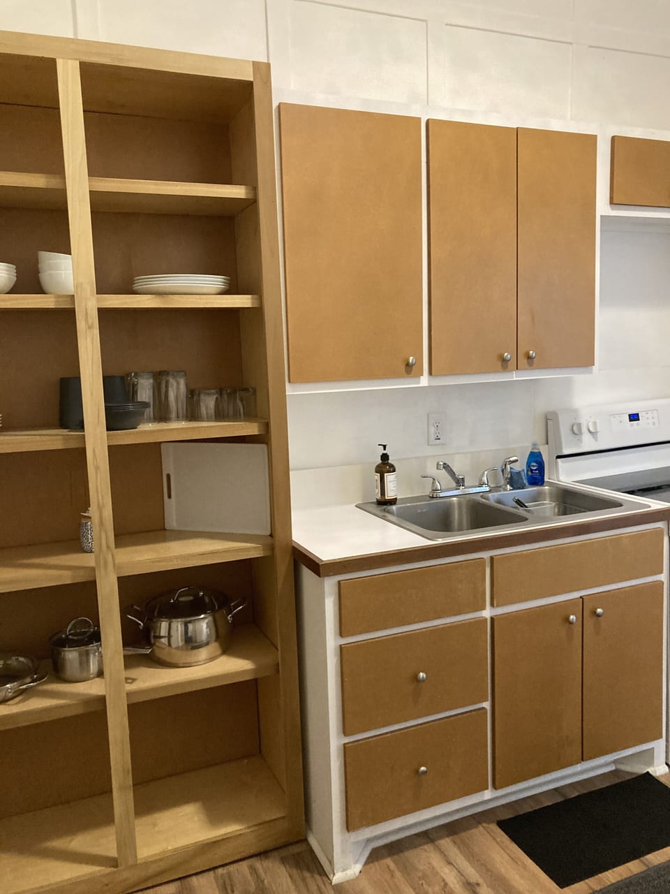 Fully stocked kitchen with refrigerator, oven, microwave, dishes, pots and pans