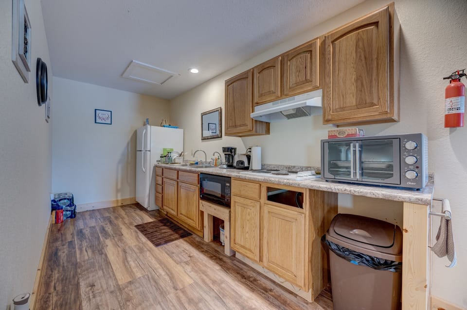 Kitchen with coffee maker, fridge, microwave and toaster oven.