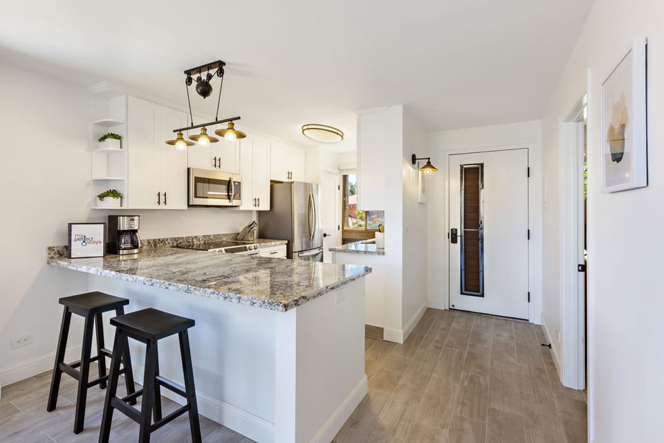 Beautiful, modern kitchen featuring bright white cabinets, stainless steel appliances and granite countertops