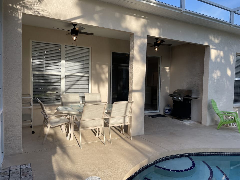 Enclosed pool with outdoor dining table for six, propane grill, and ceiling fans