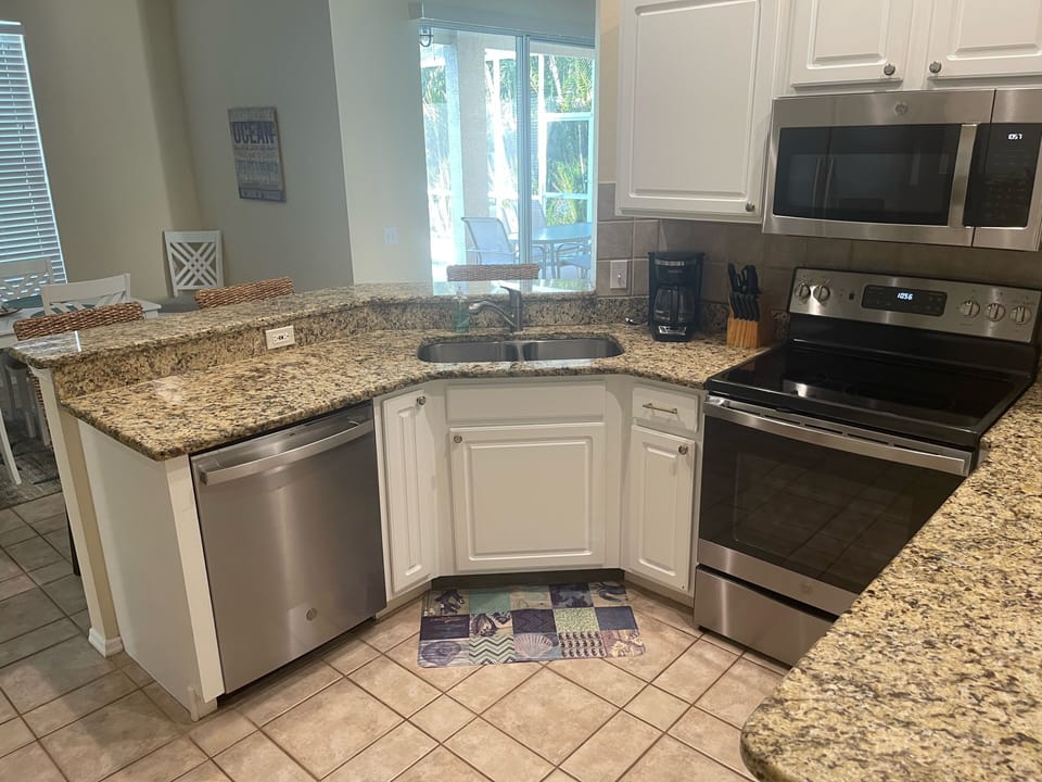 Fully stocked open kitchen with new appliances, granite countertops, 3 barstools