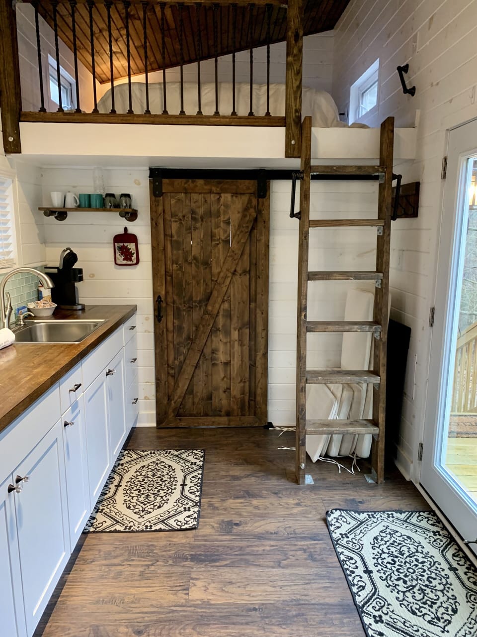 Ladder leading to queen bed, barn door leads to bathroom.
