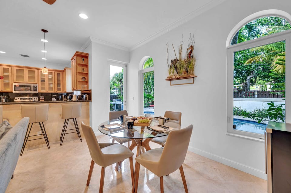 Additionally, there is a smaller table with seating for four people, perfect for enjoying breakfast or dessert while gazing out towards the heated pool.