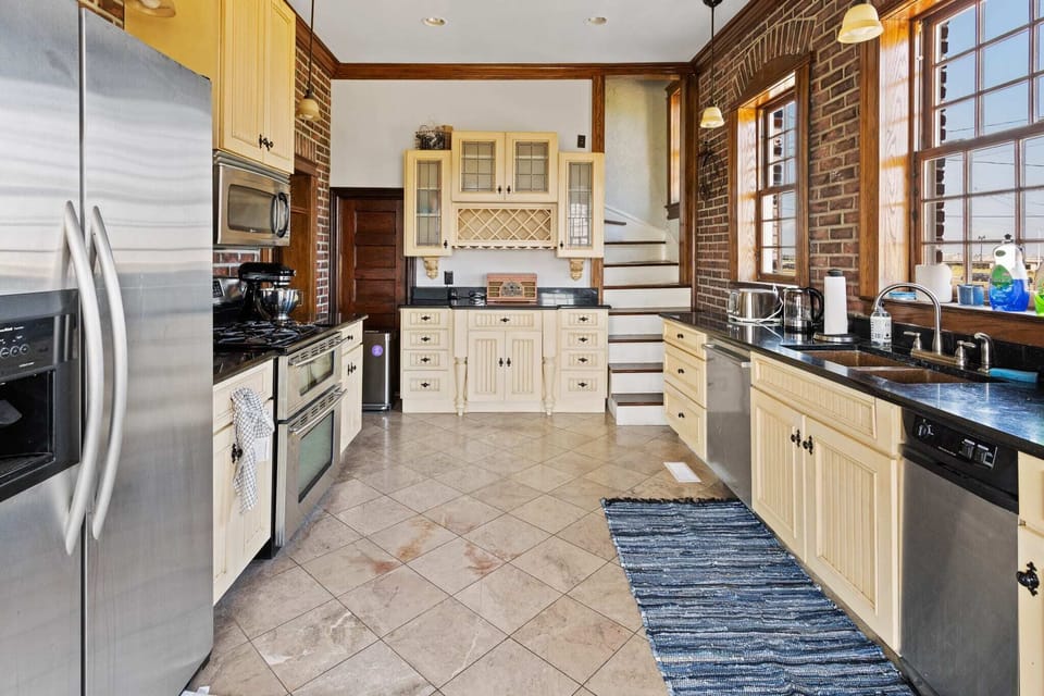 Eat-in kitchen with side-by-side refrigerator, dual oven, gas range, new Bosch dishwasher, and unique copper sink