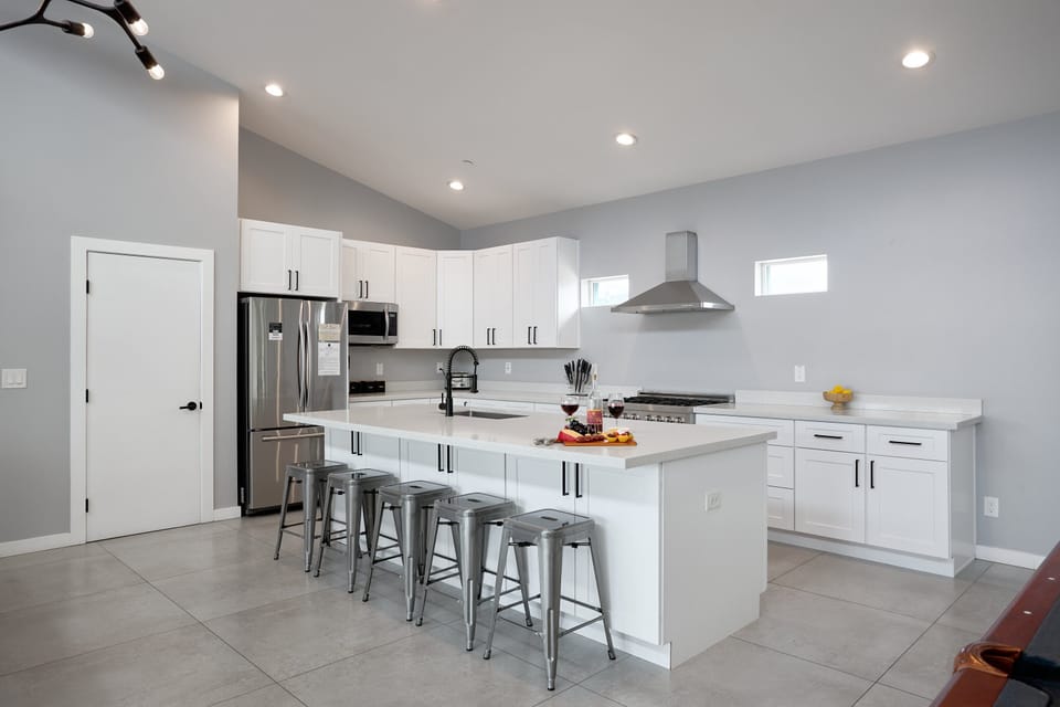Fully equipped kitchen with stainless steel appliances, a sleek kitchen island with a breakfast bar for casual seating for 5, plus a large dining table for 6.