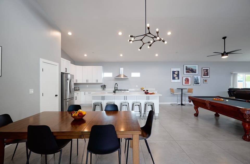 Fully equipped kitchen with stainless steel appliances, a sleek kitchen island with a breakfast bar for casual seating for 5, plus a large dining table for 6.