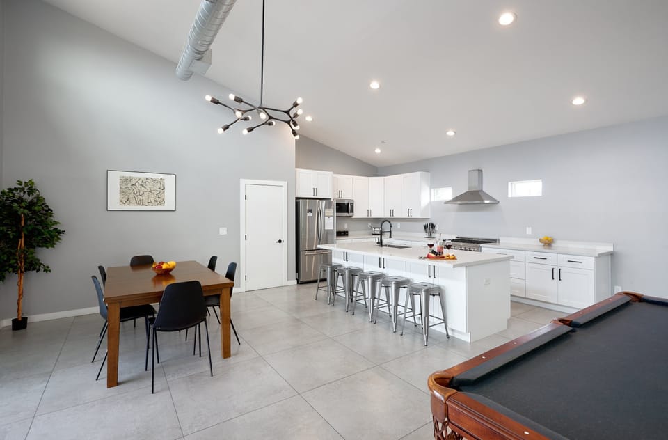 Fully equipped kitchen with stainless steel appliances, a sleek kitchen island with a breakfast bar for casual seating for 5, plus a large dining table for 6.