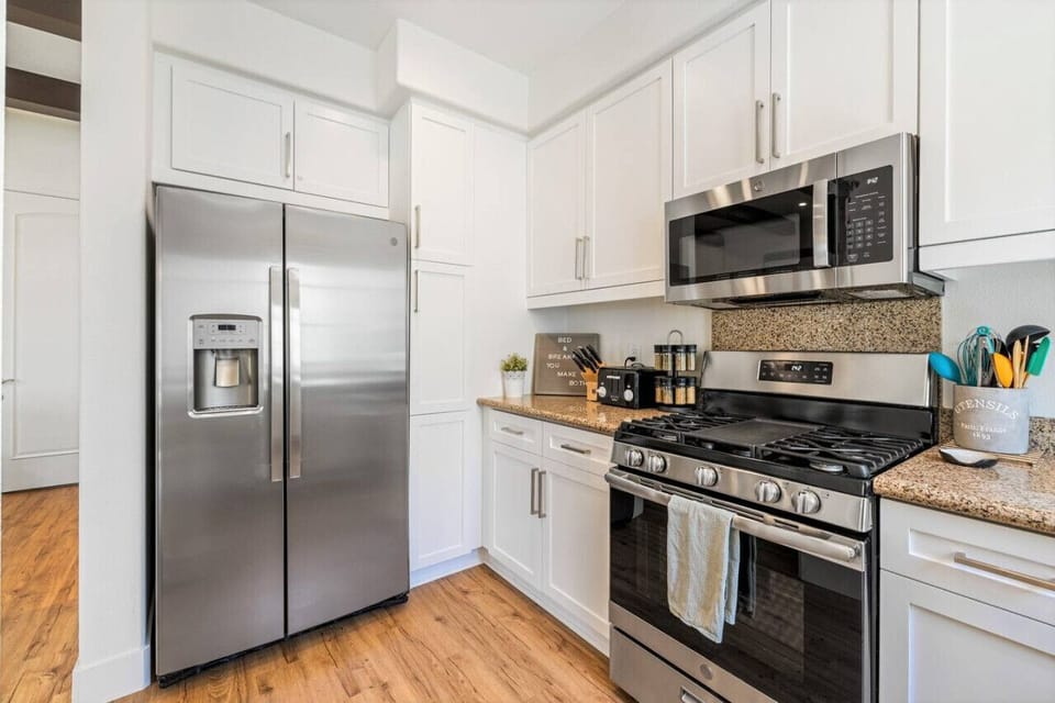 Modern white kitchen with shaker cabinets, granite counter tops and stainless steal appliances. Fridge has freezer, ice maker and  filtered water dispenser.
