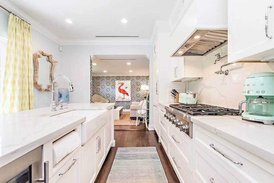 Bright modern kitchen with white cabinetry and a view into a colorful living area.