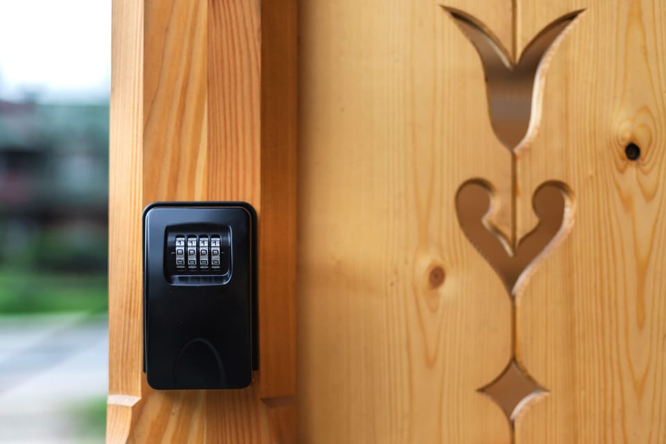  A close-up of a secure key lockbox attached to a wooden wall, ensuring safety and convenience for guests.