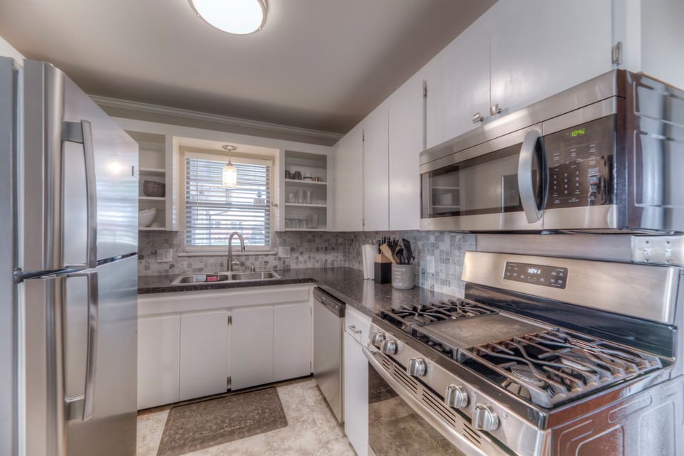 Kitchen with full size fridge, gas stove and oven, microwave and small appliance