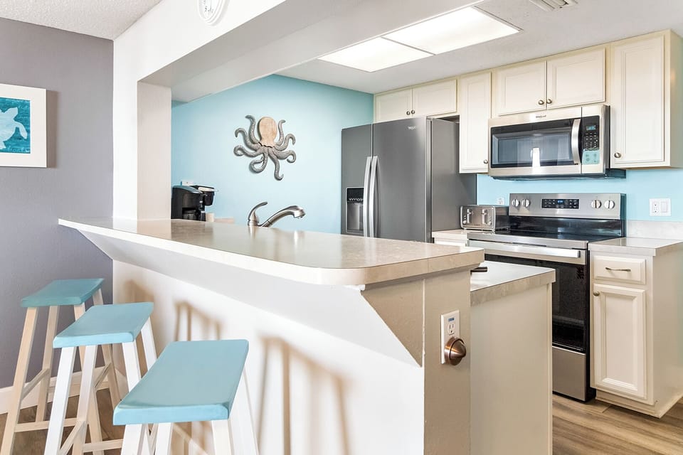 Chat and snack around the cheerful breakfast bar or whip up tasty meals—your cozy coastal kitchen awaits!