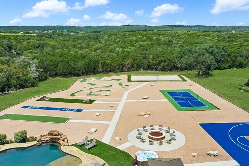[Backyard] Aerial view of the outdoor amenities featuring a hot tub and fire pit, pickleball, volleyball, basketball and more