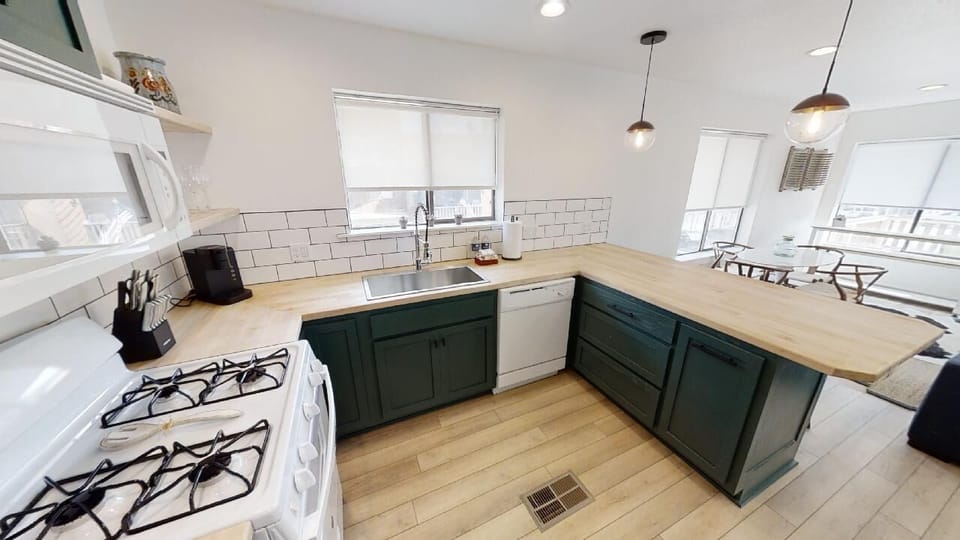 Your spacious kitchen blends style and function with deep green cabinetry, butcher-block counters, and modern appliances. Bright windows and sleek pendant lighting create a welcoming space where you can cook, gather, and make memories.