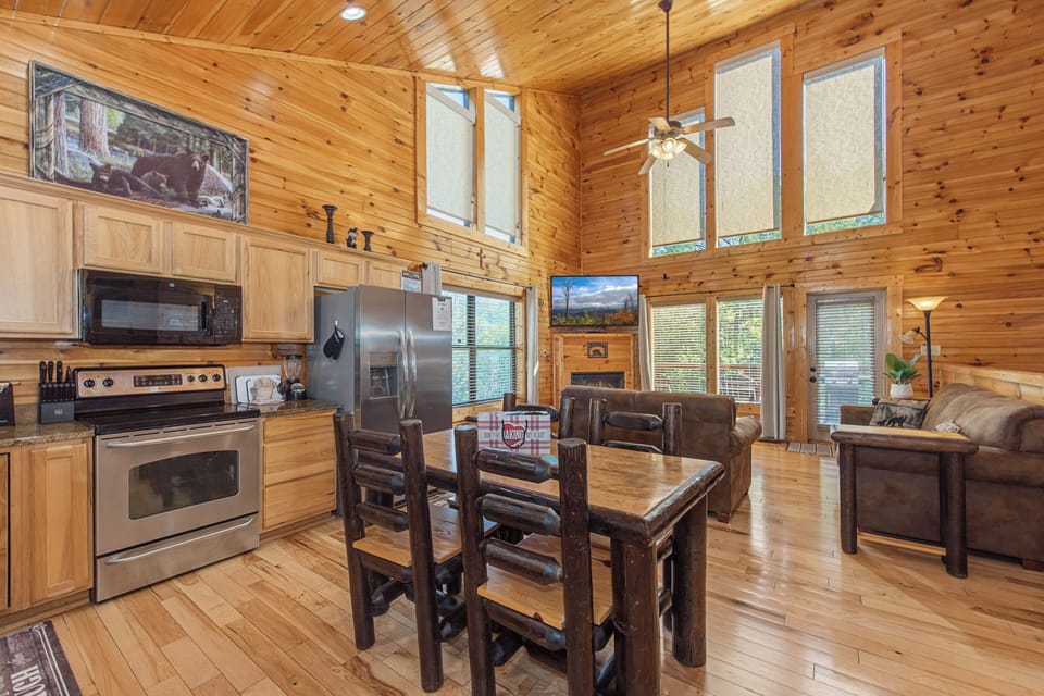 Relax in your open-concept cabin with warm wood accents, fully equipped kitchen, and cozy dining space perfect for mountain meals.
