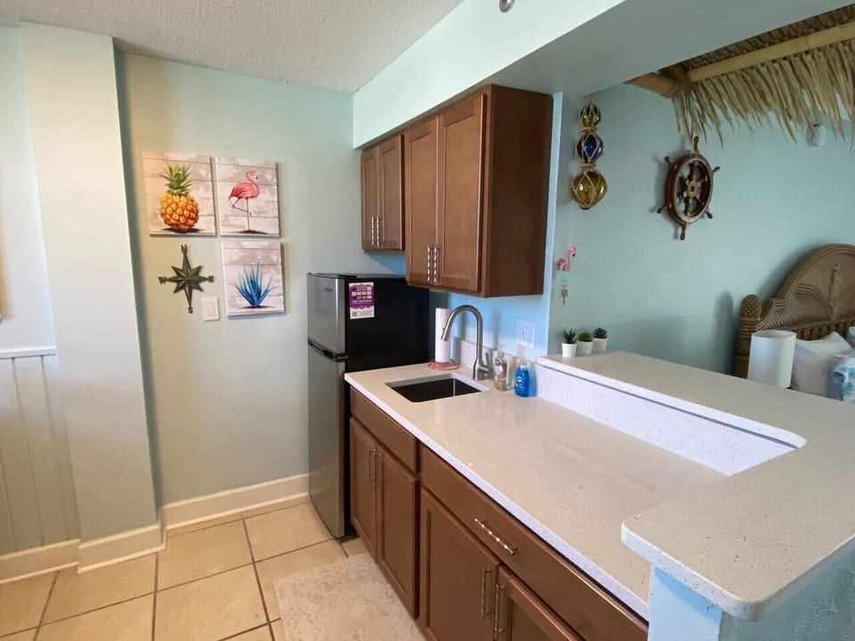 Roomy remodeled kitchenette with quartz counters and a big fridge