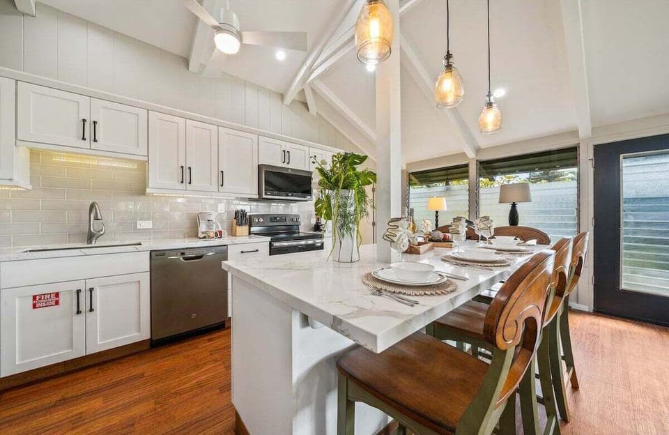 Full kitchen featuring white cabinets, stainless steel appliances, and island seating