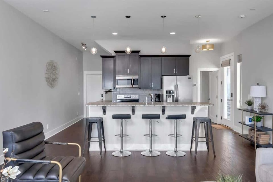 Sleek white kitchen featuring gray cabinets, a spacious island, and stylish high chairs.
