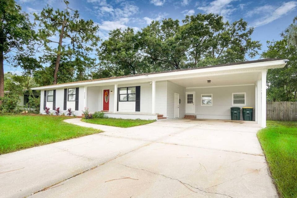 Welcoming home with charming curb appeal, a bold red door, and a spacious driveway for easy parking.
