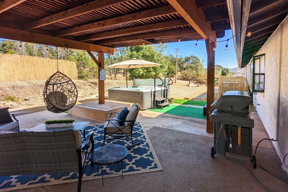 A covered patio sets the scene for outdoor lounging, grilling, and a relaxing soak in the hot tub.