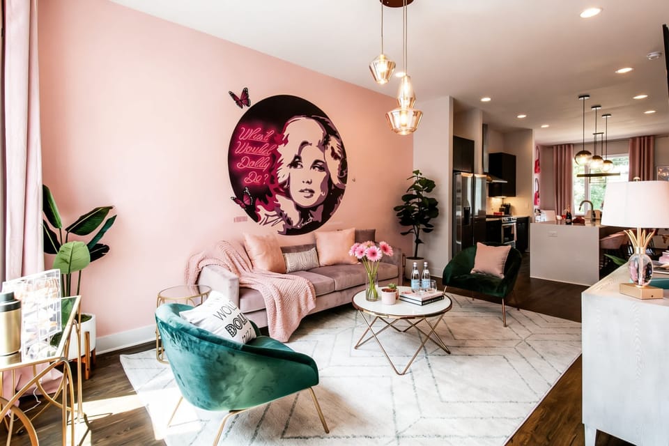 The living room is wrapped in pink and Dolly devotion. A sofa and armchairs circled around a coffee table make it easy for the group to stay close between outings