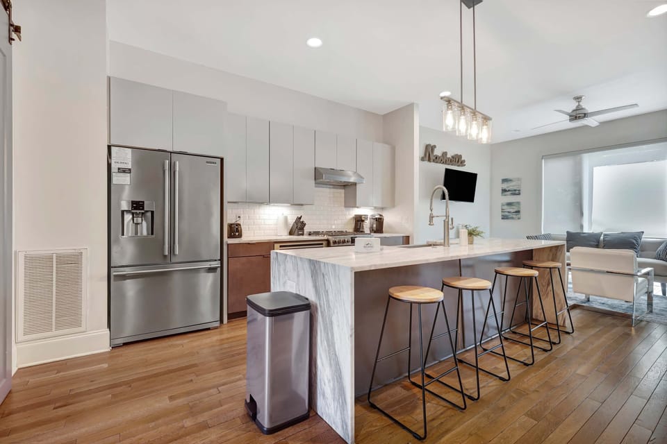 Open-concept kitchen with center island and bar seating, seamlessly flowing into the cozy living room—ideal for entertaining and group gatherings