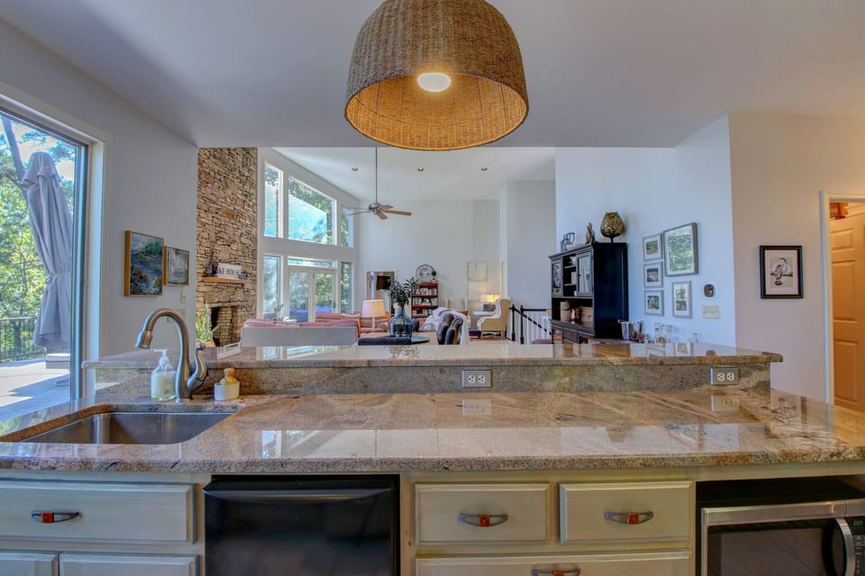 Kitchen island with ice maker and microwave opens to vaulted living and dining.