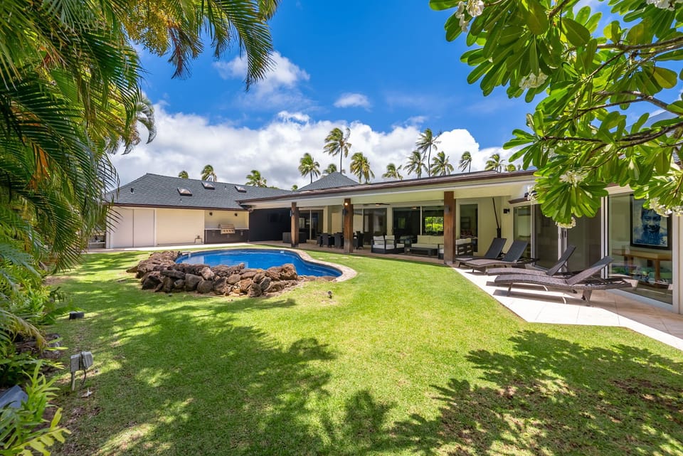 Expansive backyard and sparkling pool framed by lush greenery—your private oasis in upscale Kahala.