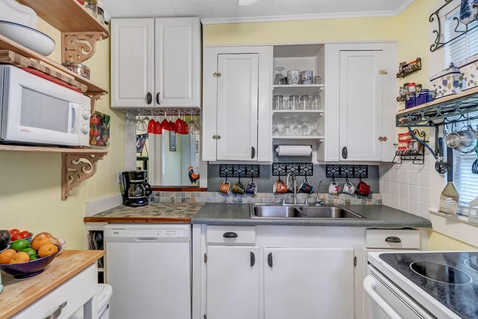 - Cook in this adorable vintage kitchen featuring white cabinetry and open glass storage
- Tile backsplash and quirky accents create a cozy, personalized atmosphere
- Everything you need is within reach for meals and snacks