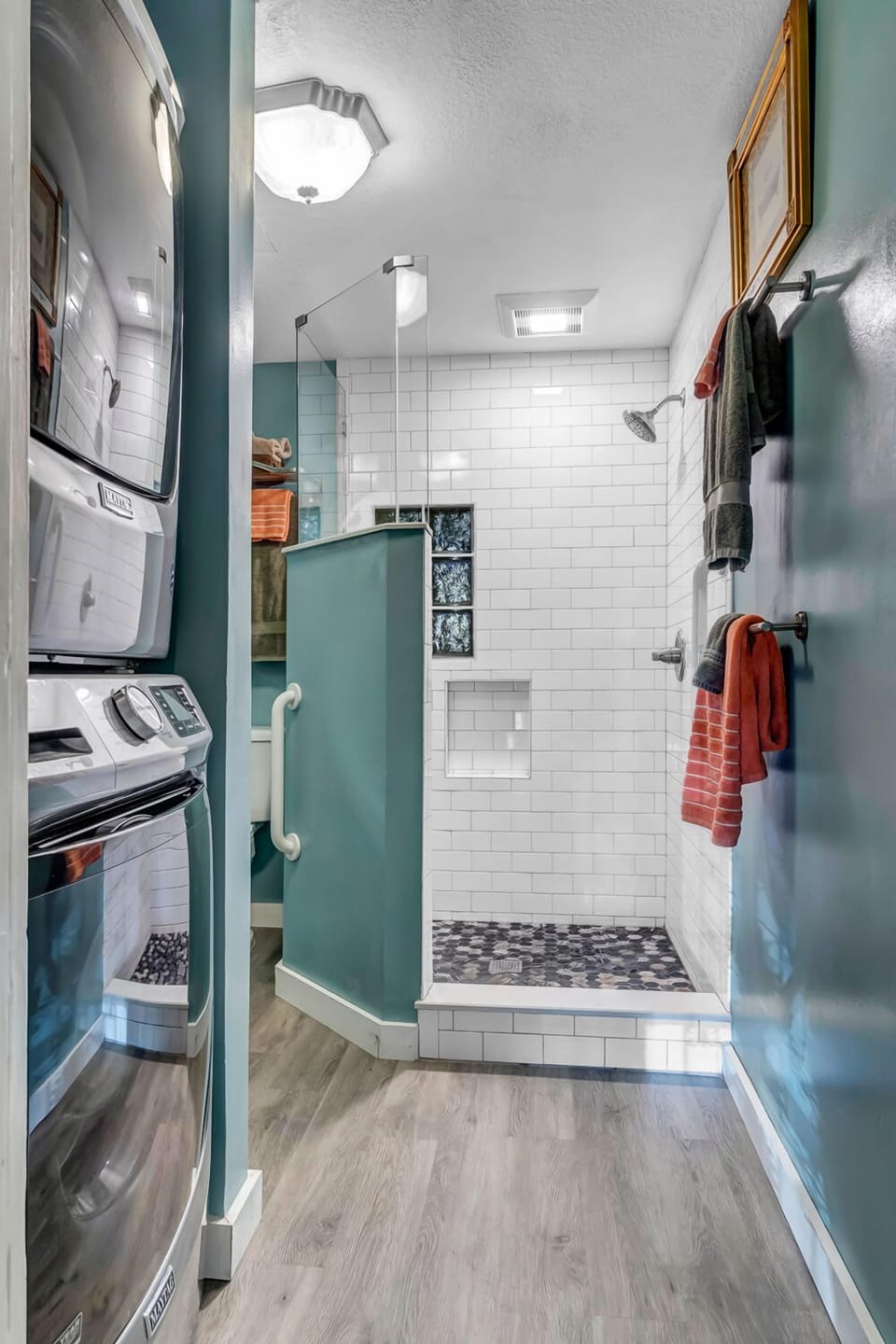 - Conveniently placed near the bath, the stacked washer and dryer offer easy access
- Shower in style with glass block details, mosaic tile flooring, and dual towel hooks
- Combined space perfect for longer stays and family trips