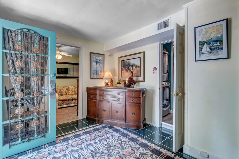 - Enter through a colorful teal door into a warm and welcoming foyer with classic charm
- Wood furnishings and framed artwork create a cozy first impression
- Connects easily to main living spaces and colorful guest rooms beyond