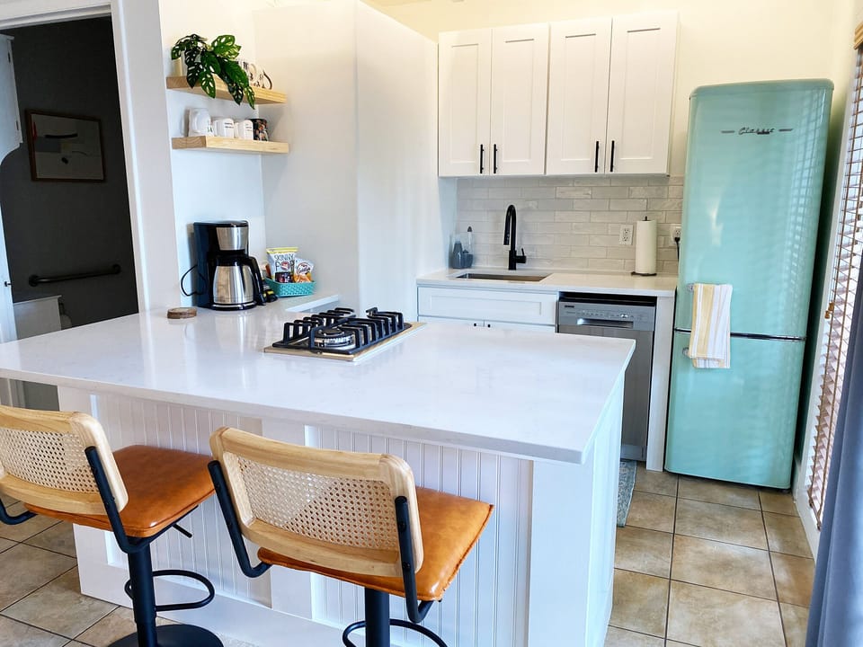 Kitchen with gas cooktop, fridge/freezer, dishwasher, and barstool seating.