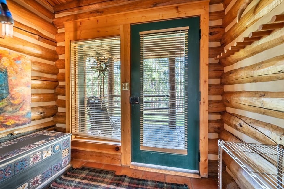Step into your charming log cabin retreat where rustic wood walls and colorful artwork create a warm, welcoming atmosphere at your private entrance.