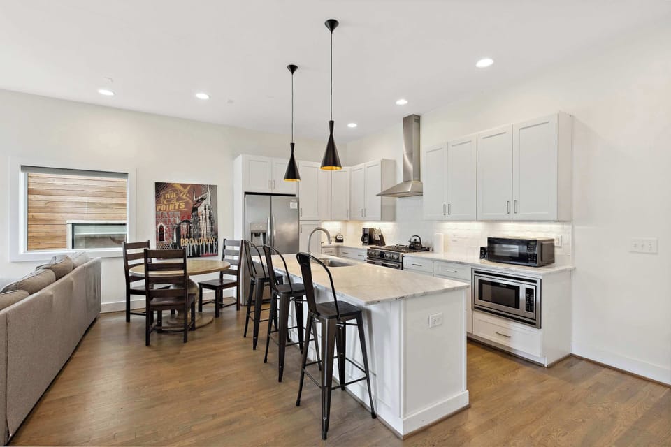 Fully equipped kitchen with stainless steel appliances and island seating for three, perfect for cooking and casual dining.