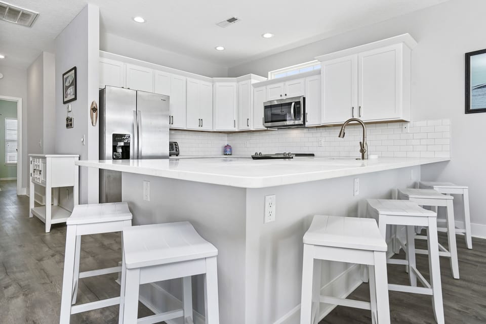 Your sleek white kitchen features modern appliances and a spacious island with bar seating—perfect for preparing meals and casual dining together.