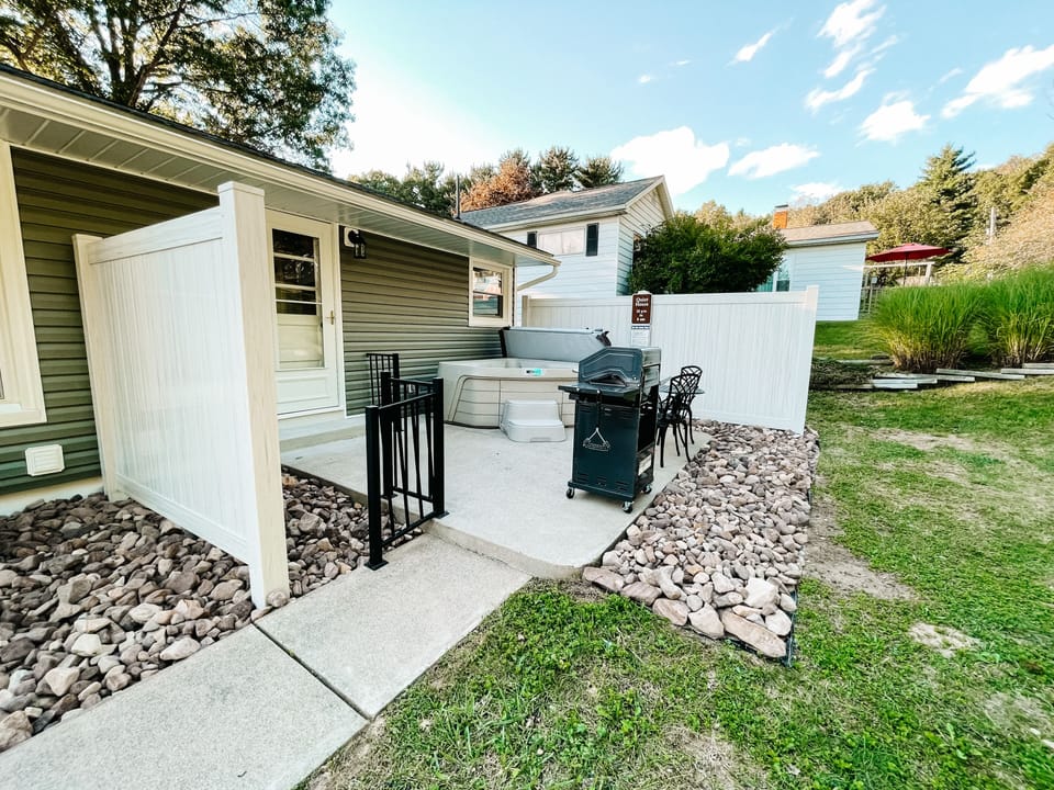Outdoor patio space with hot tub and grill. 