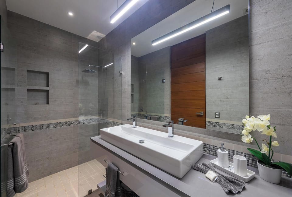 Get ready at a modern floating vanity featuring a wide basin counter, polished mirror, and a seamless glass walk-in shower stall.