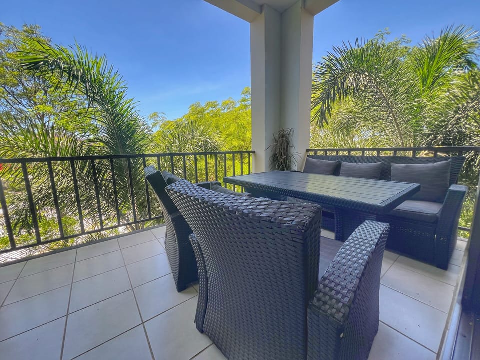 The covered balcony has tropical views and comfy seating.