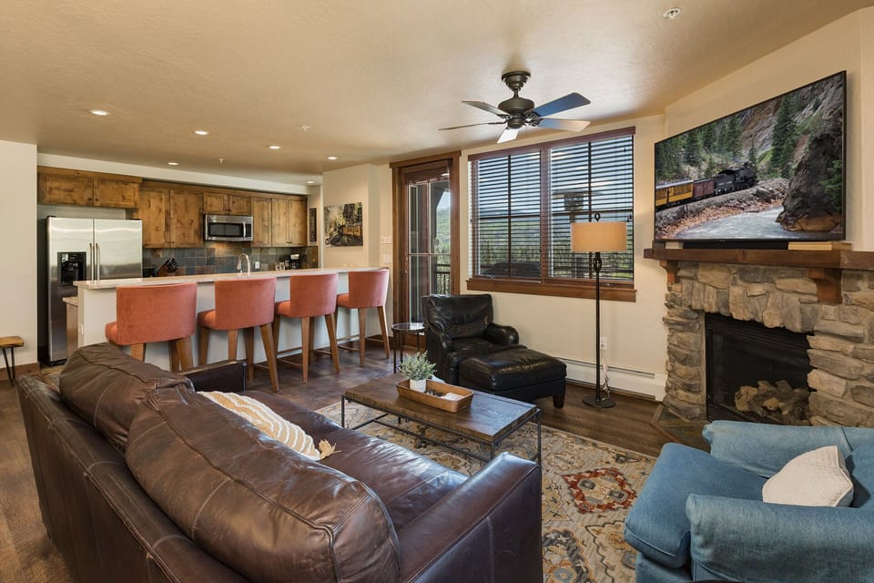 Living room with gas fireplace, TV, and mountain views. Queen pull out sofa. Access to outdoor patio. Great views of the slopes!