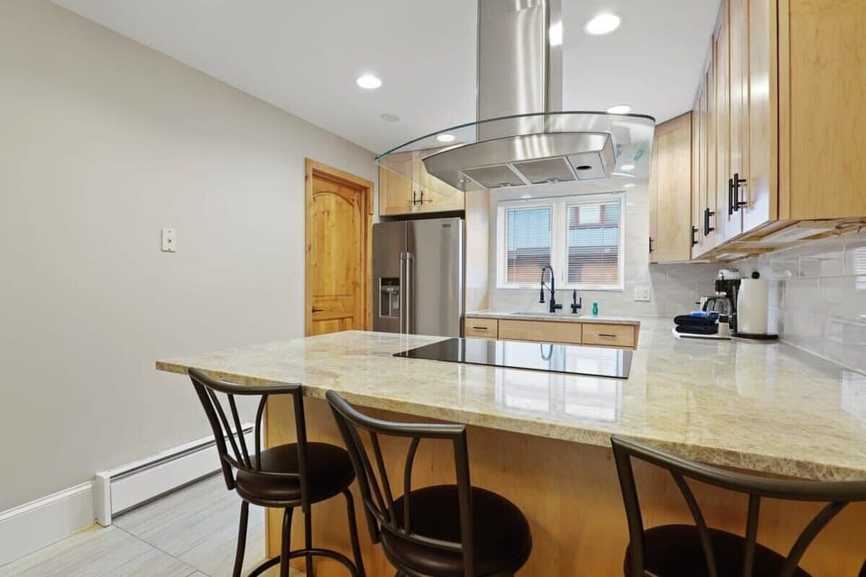 Fully-equipped kitchen with stainless steel appliances and 3 bar stools
