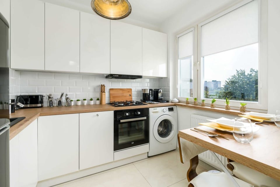A modern kitchen with built-in appliances, a washing machine, and ample counter space.
