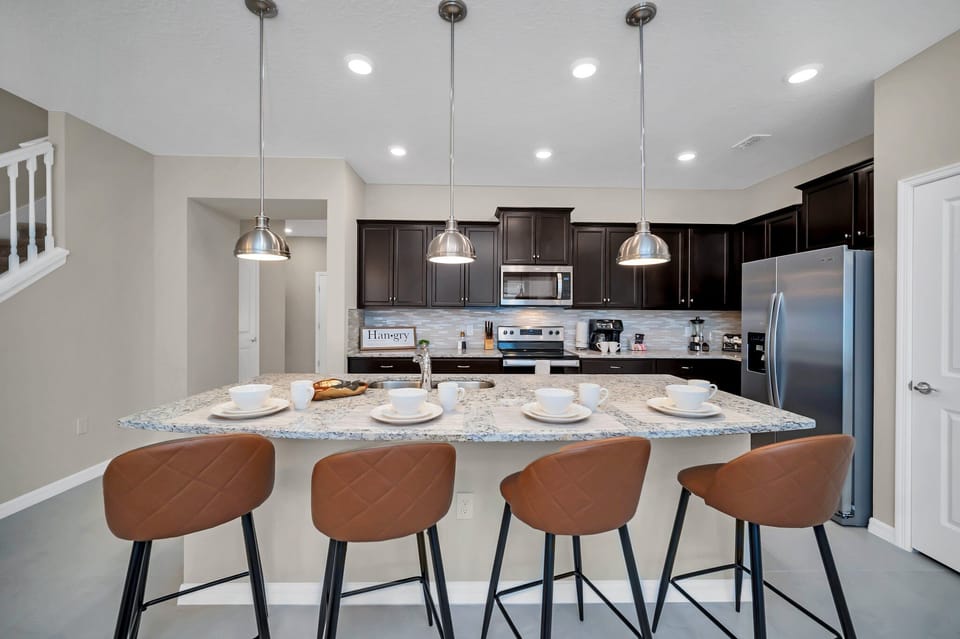 Contemporary open concept Kitchen with countertop and high chairs for a quick coffee or snack fronting the living room