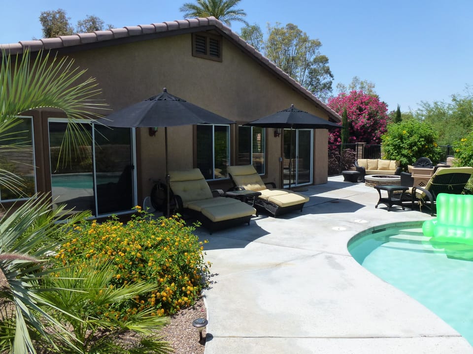 Pool area showing 3 luxurious double loungers, 2 large umbrellas & fire pit