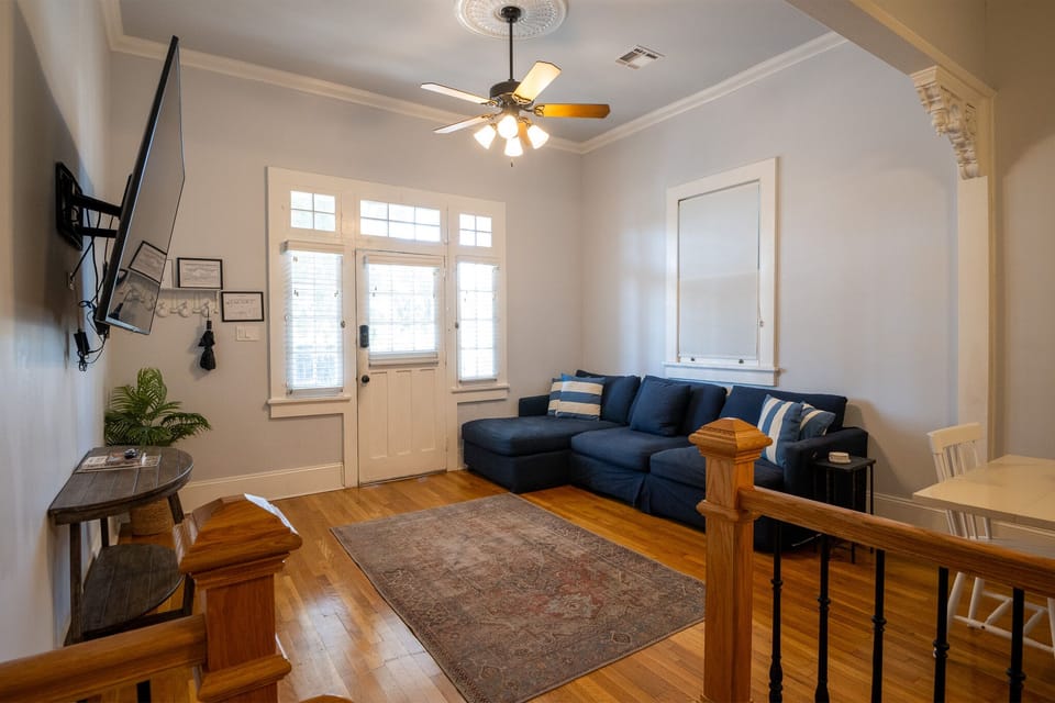 A large sectional sofa, 60” flat-screen TV, and ceiling fan around carpentry.