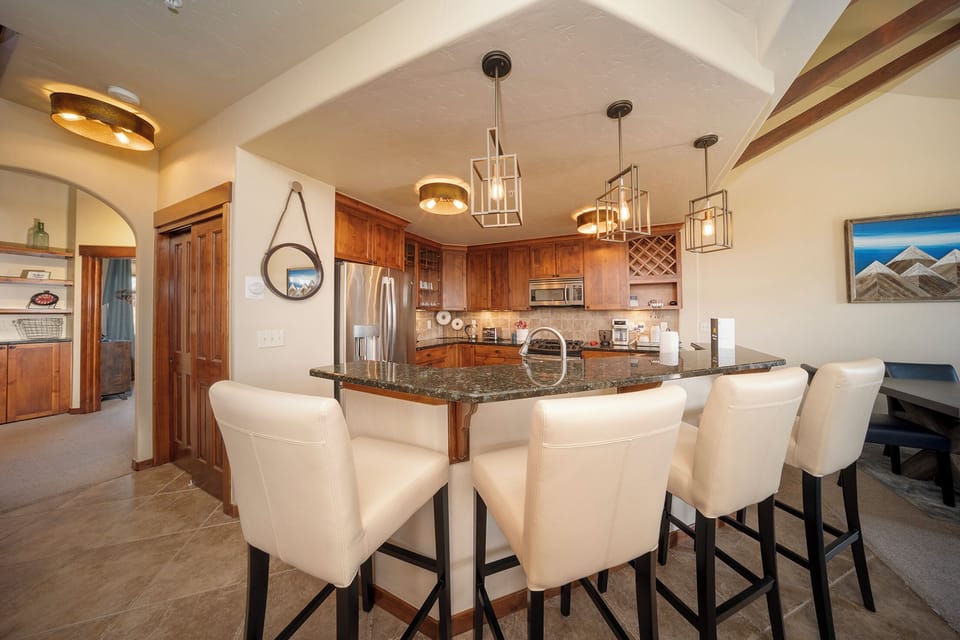 - Kitchen bar with seating for four and pendant lighting above   - Stainless steel appliances and stone counters for easy cooking   - Open design connects to dining and living for shared meals