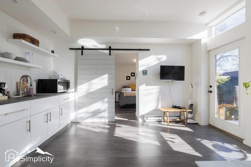 - Open plan space with smart TV, dining area, and kitchenette seamlessly connected
- Sliding barn door leads to a comfy private bedroom for restful nights
- Bright natural light fills the room, making it feel cheerful and welcoming